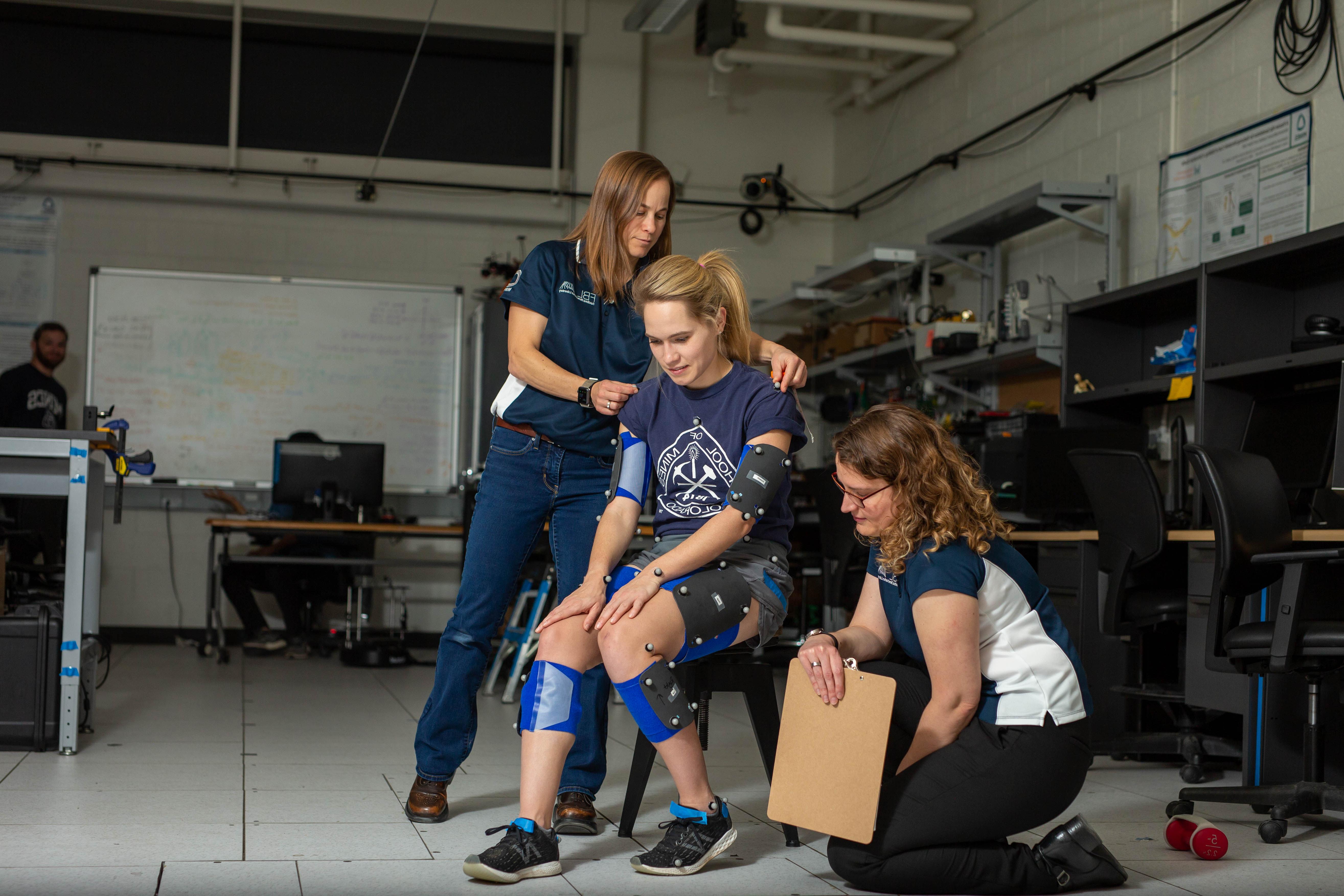 lab participant seated with sensor pads in biomechanics lab