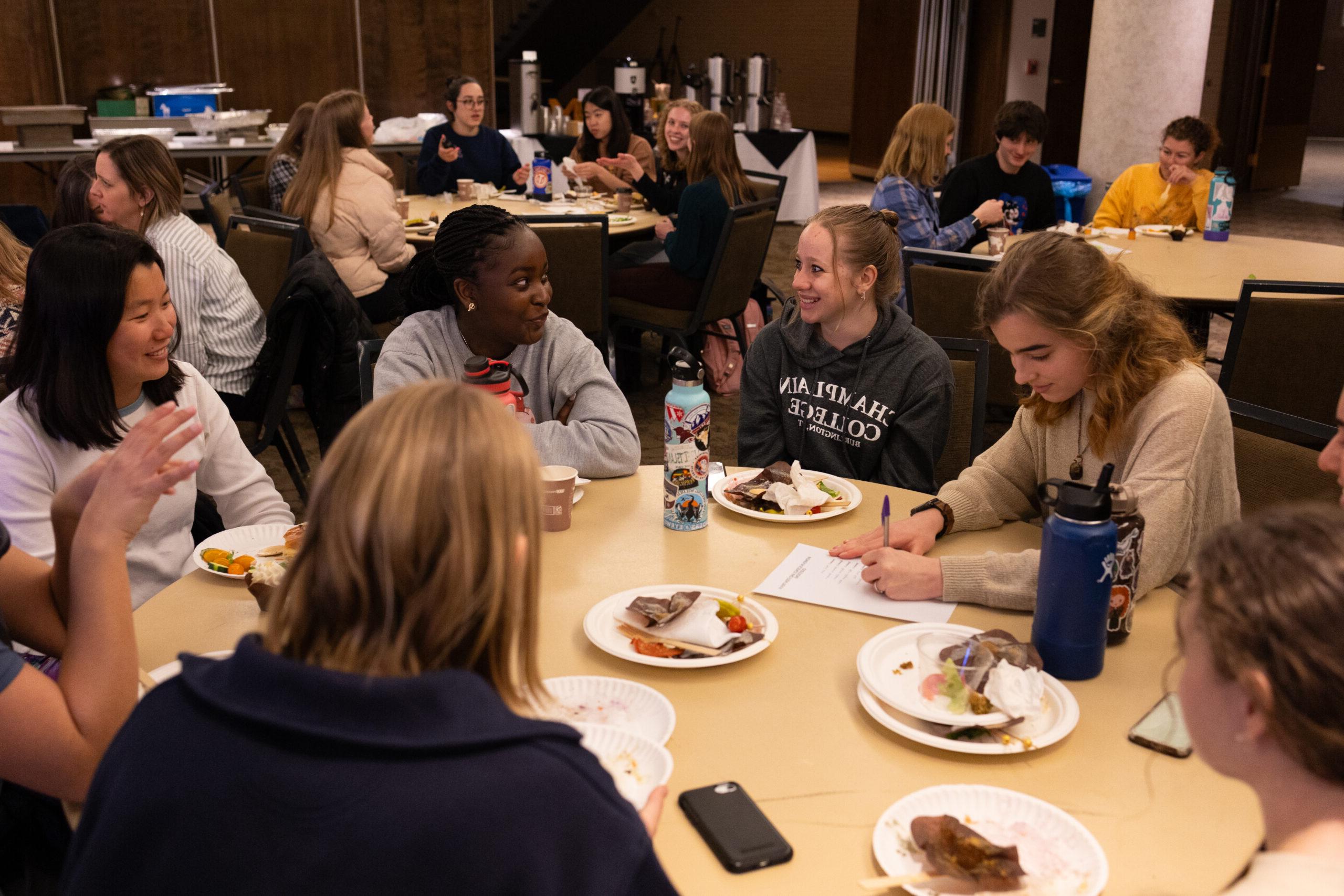 Women sitting at tables in a conference room, playing trivia, eating lunch